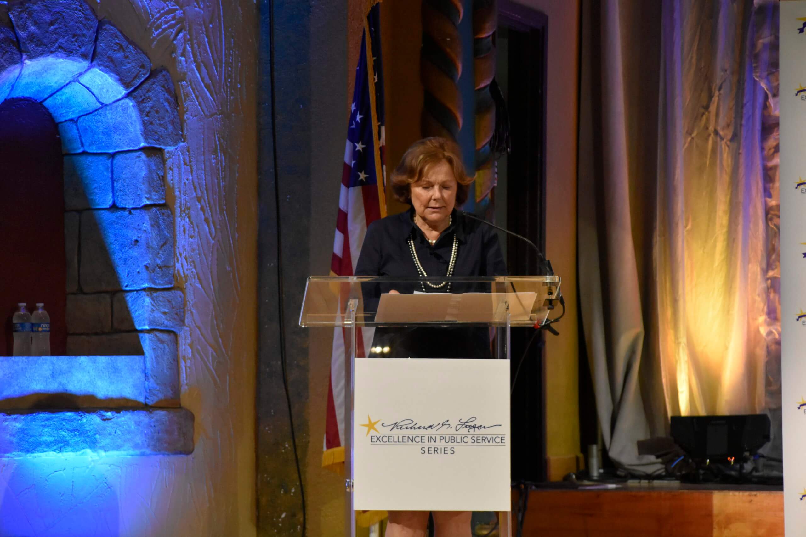 Lugar Series Co-Founder Judy Singleton speaks at the podium