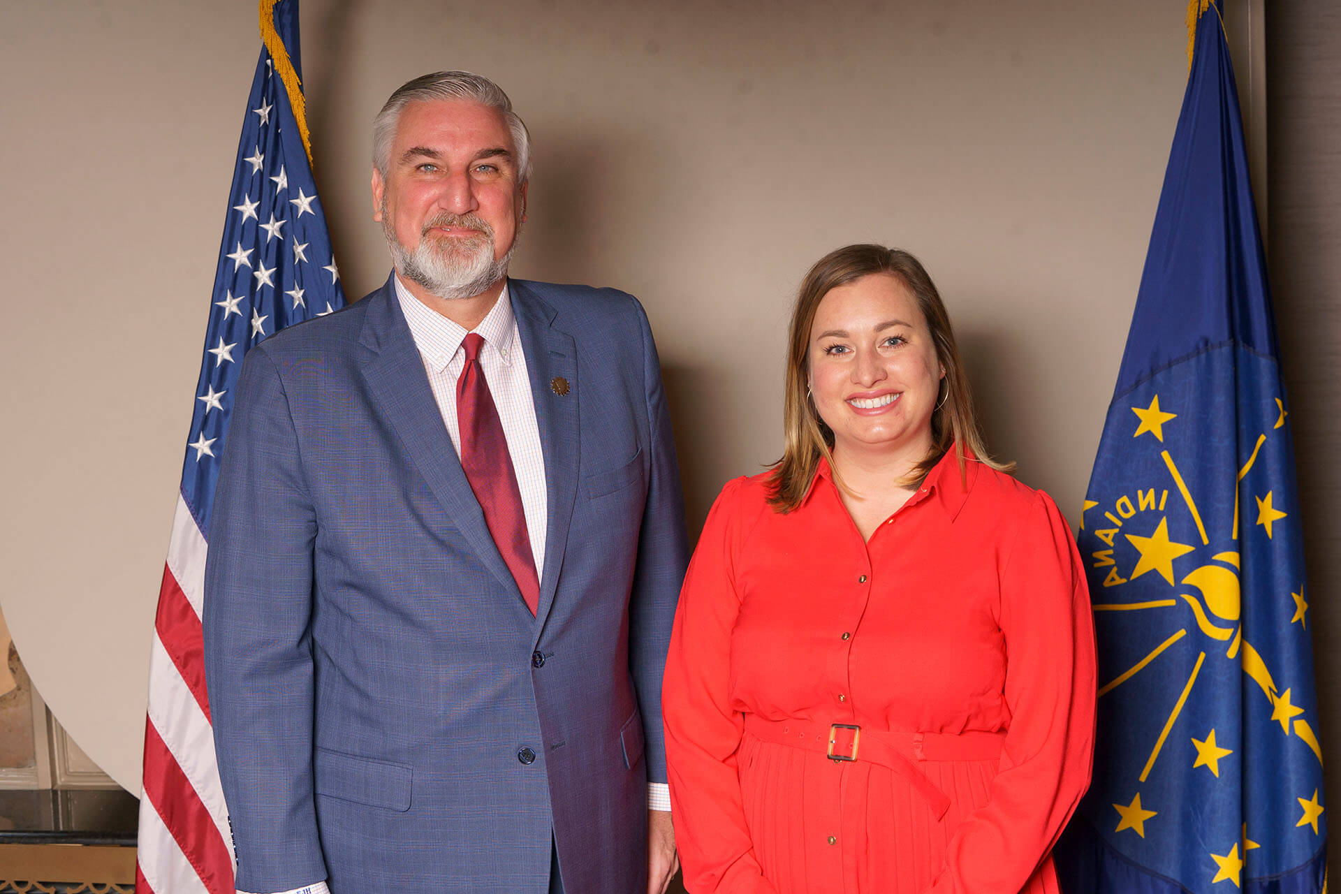 Lugar Series member wearing a red outfit poses with a man and flags