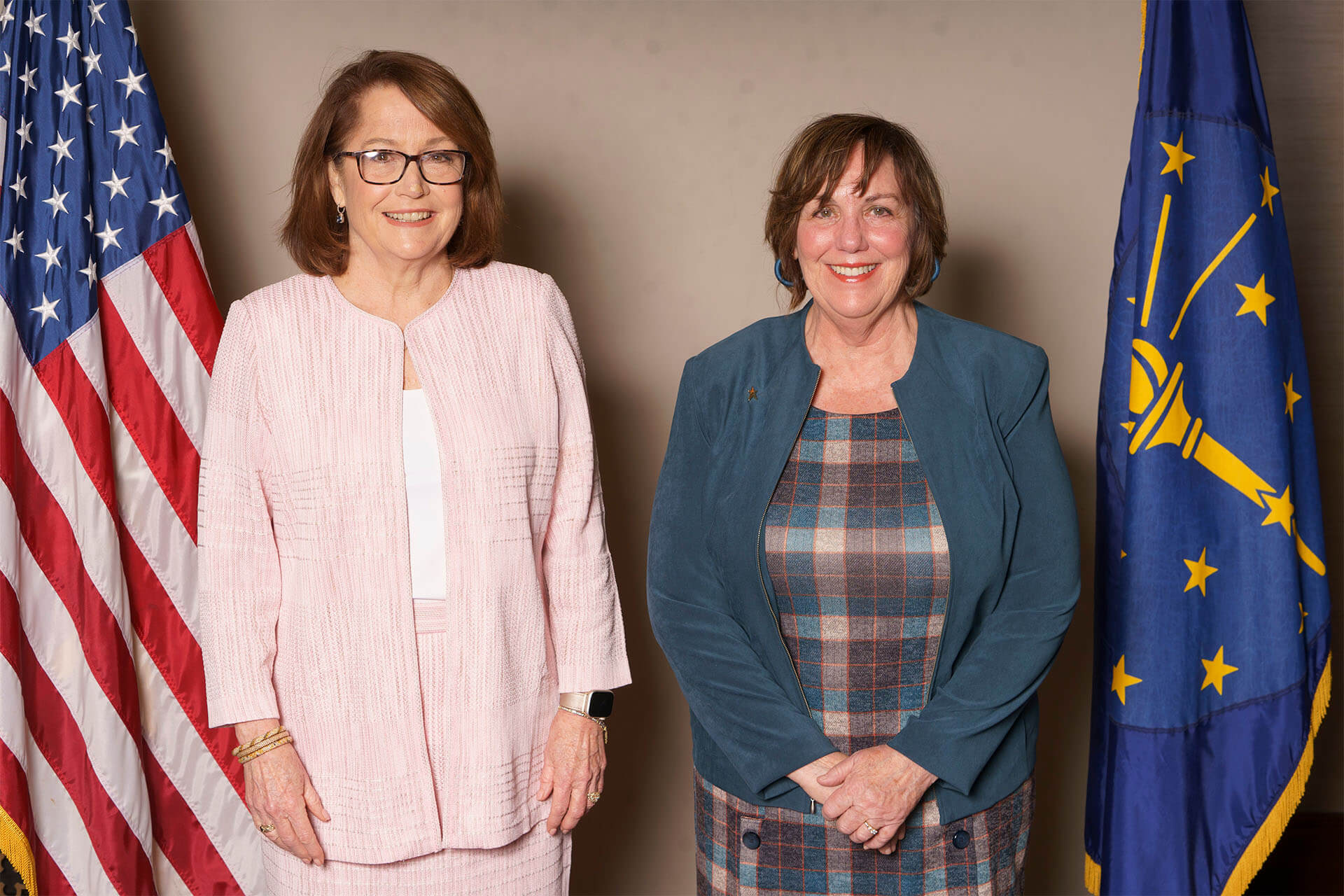 Two members of the Lugar Series smile in front of flags
