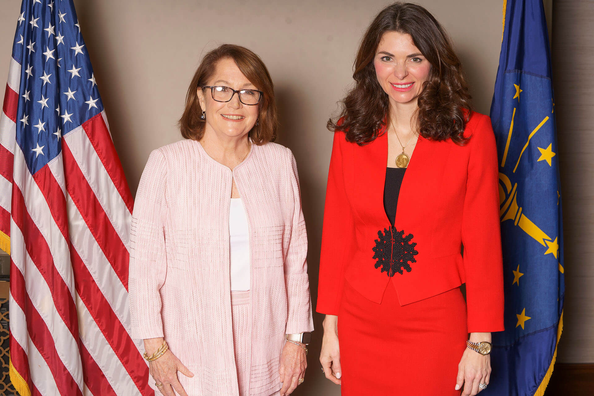 Two women at the Lugar Series event in front of flags — the woman on the right is wearing a red outfit