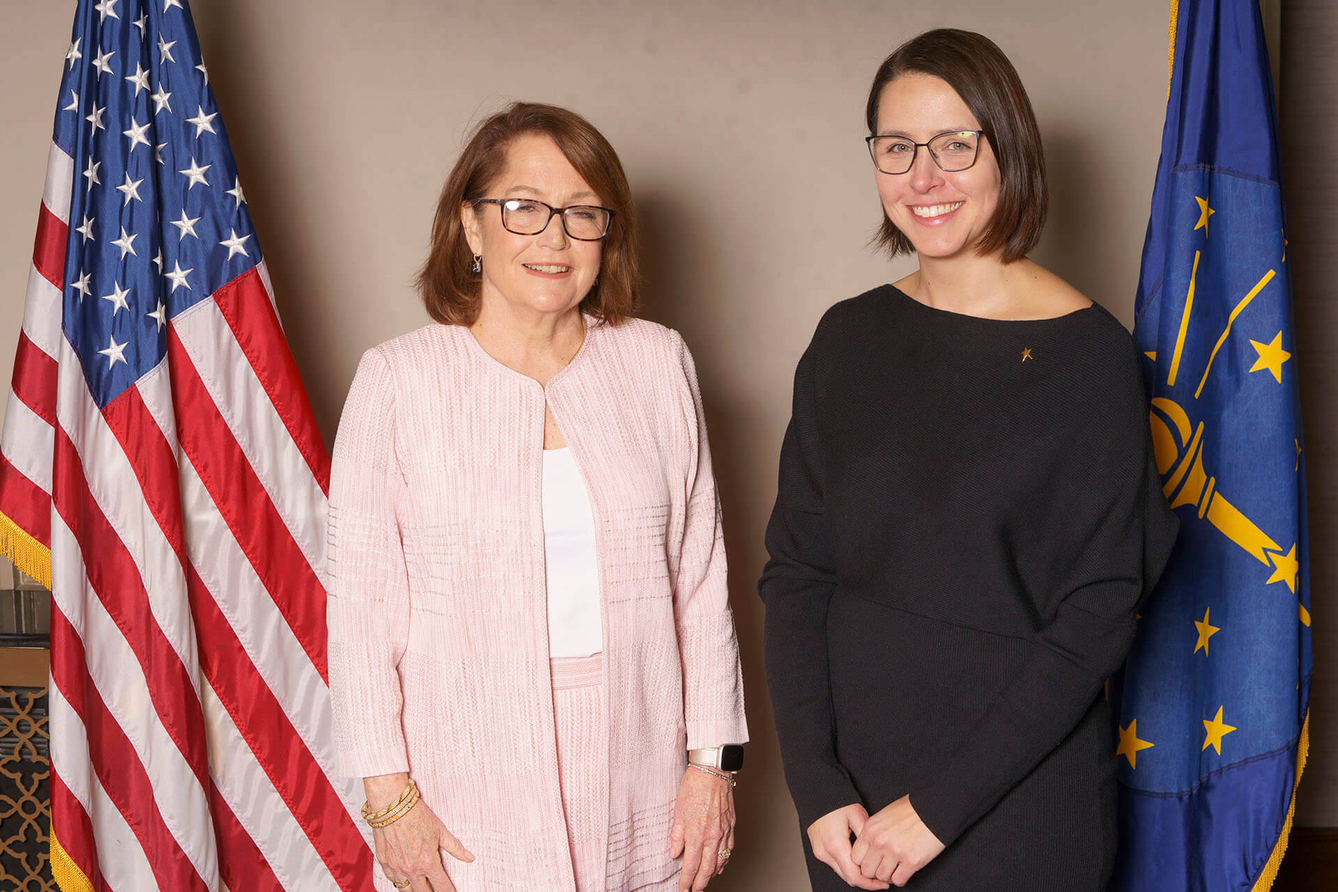 Lugar Series event photo with two women and flags — the woman on the right wears a black dress