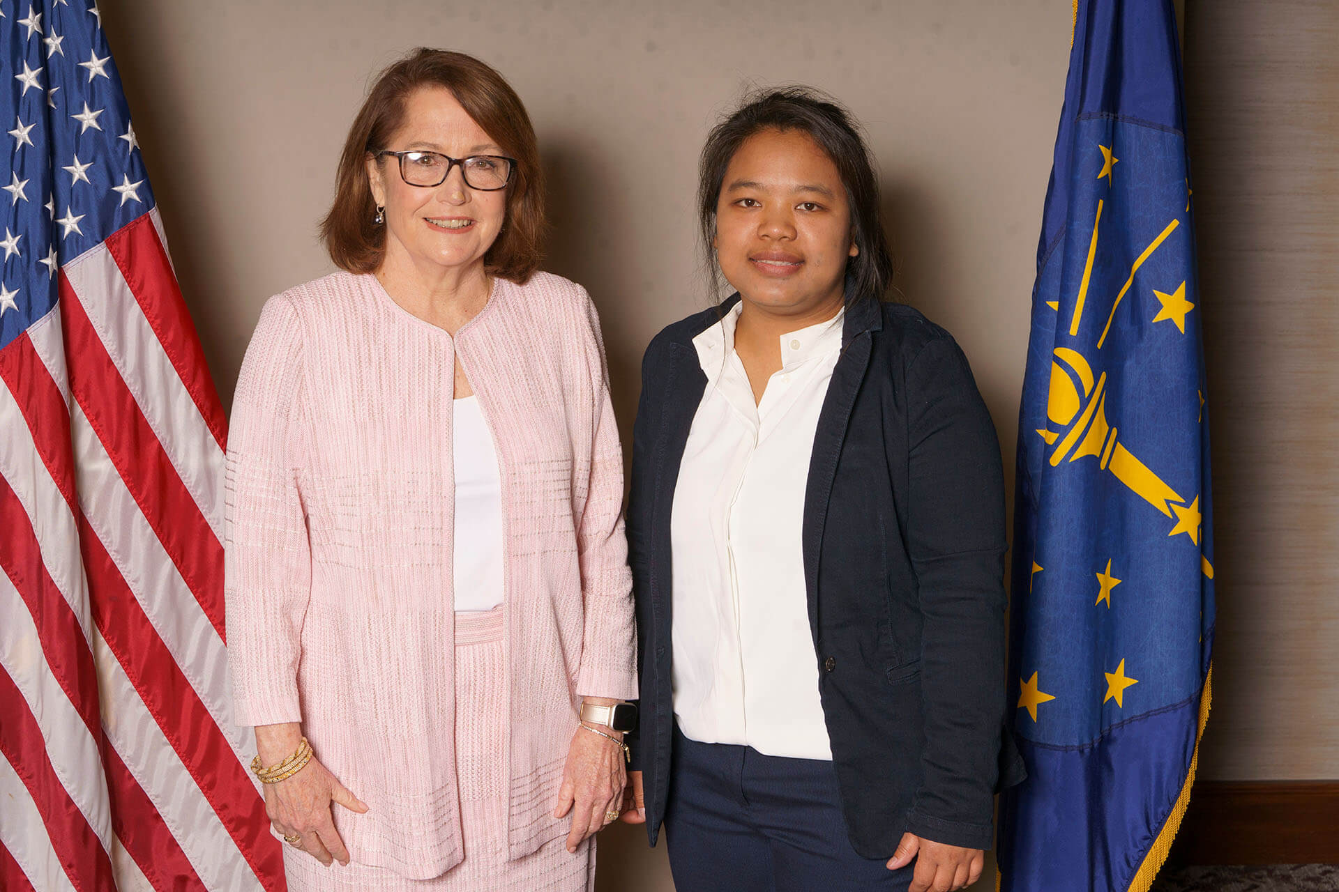 Two women standing with flags behind them