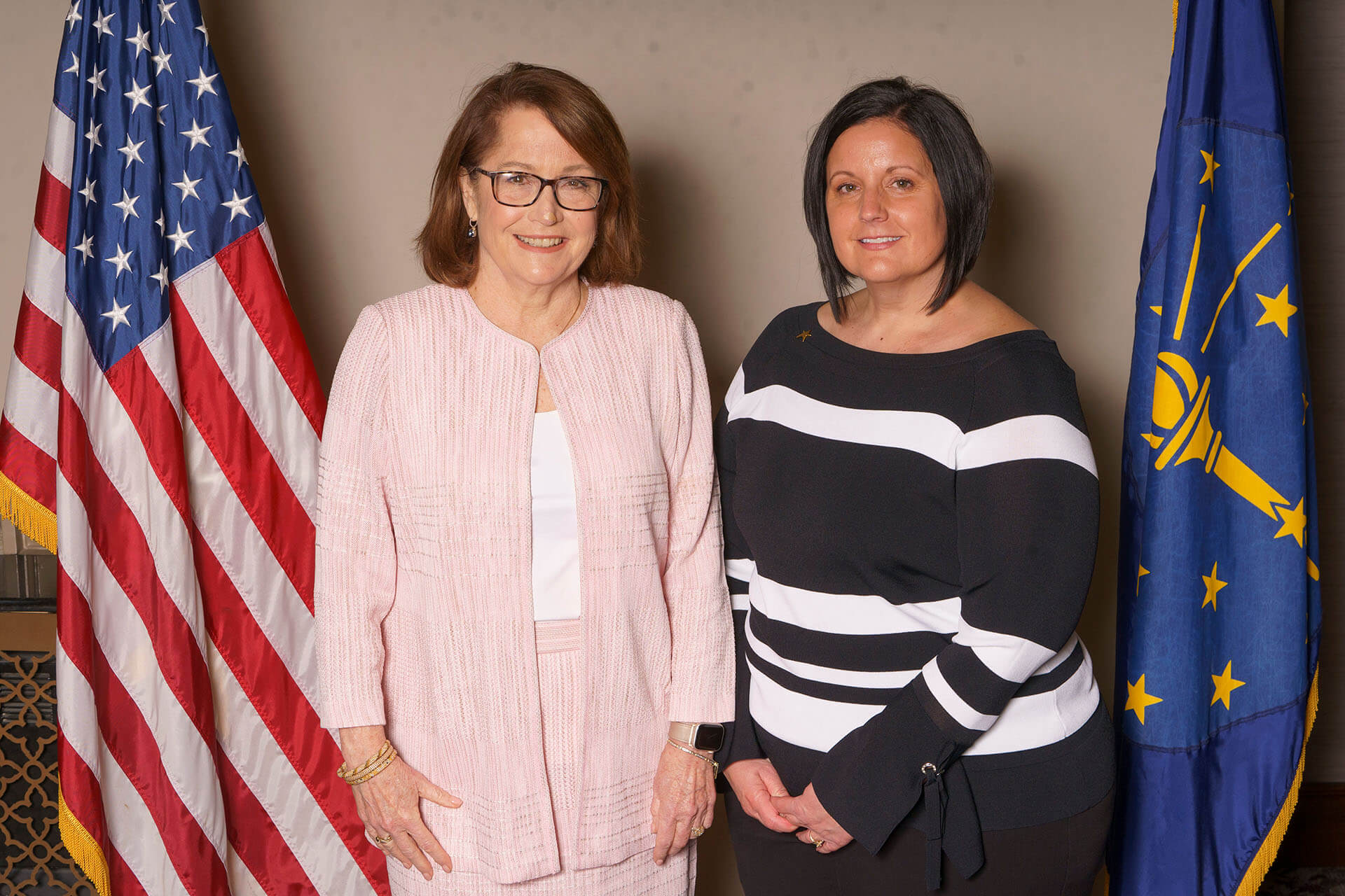Two Annual Luncheon attendees in front of flags