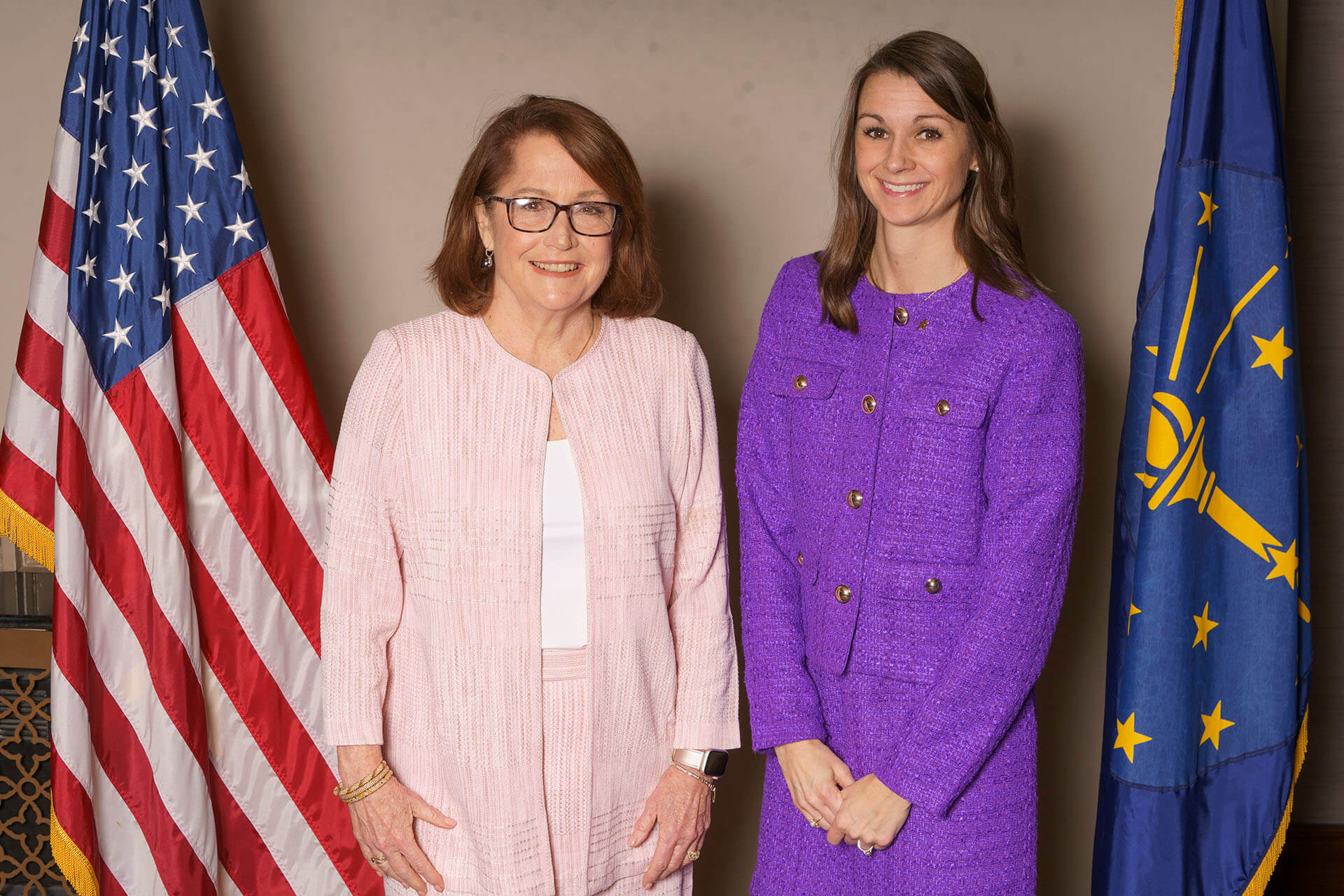 Lugar Series members at Annual Luncheon with flag backdrop — one of the women wears a purple outfit