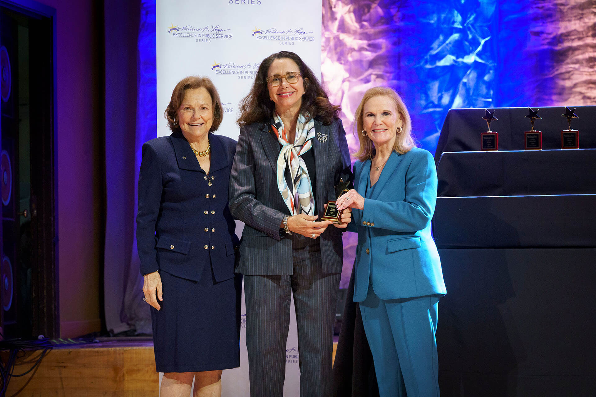Lugar Series member wearing a scarf is presented with an award at the Annual Luncheon