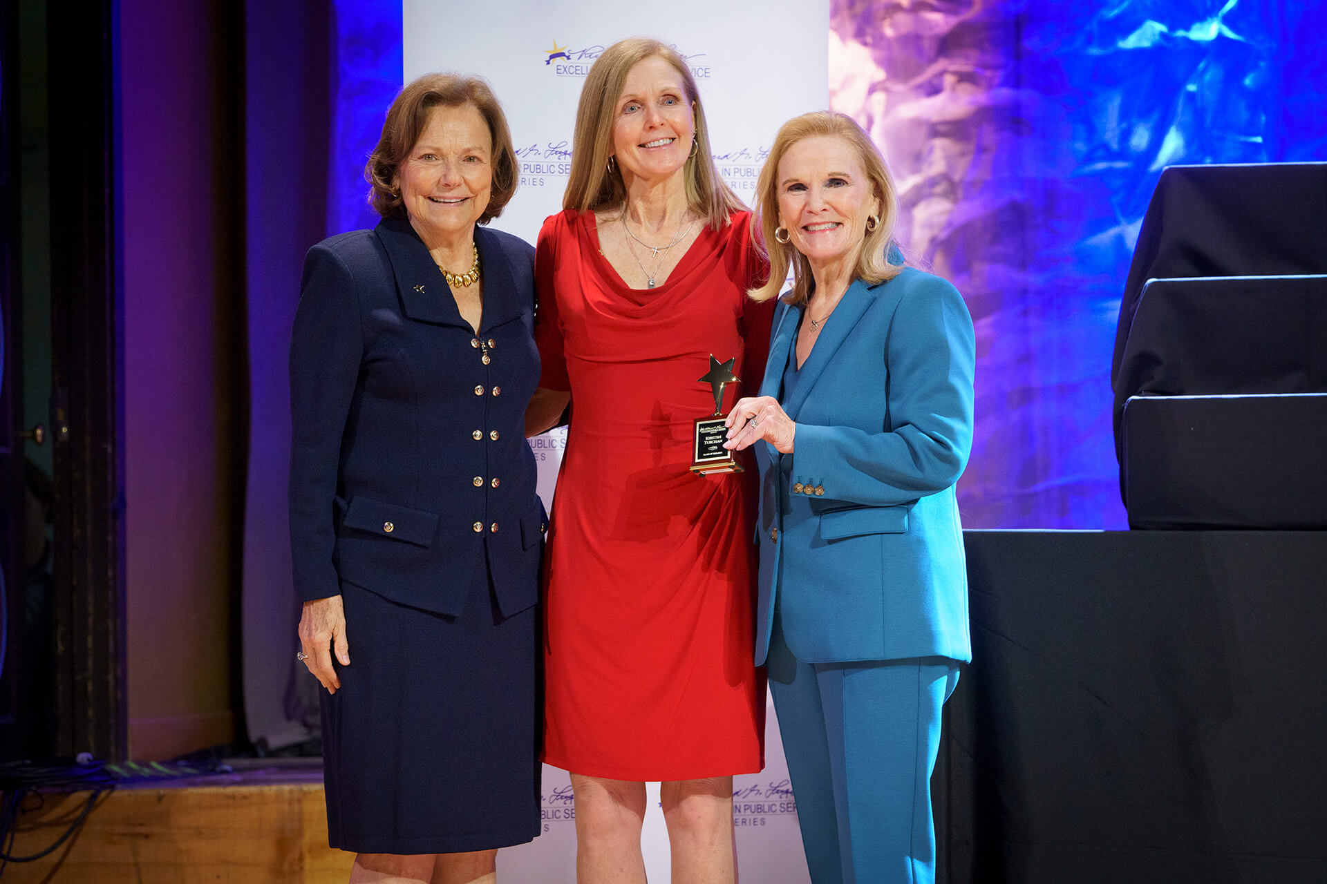 Lugar Series member wearing a red dress receives an award at the Annual Luncheon