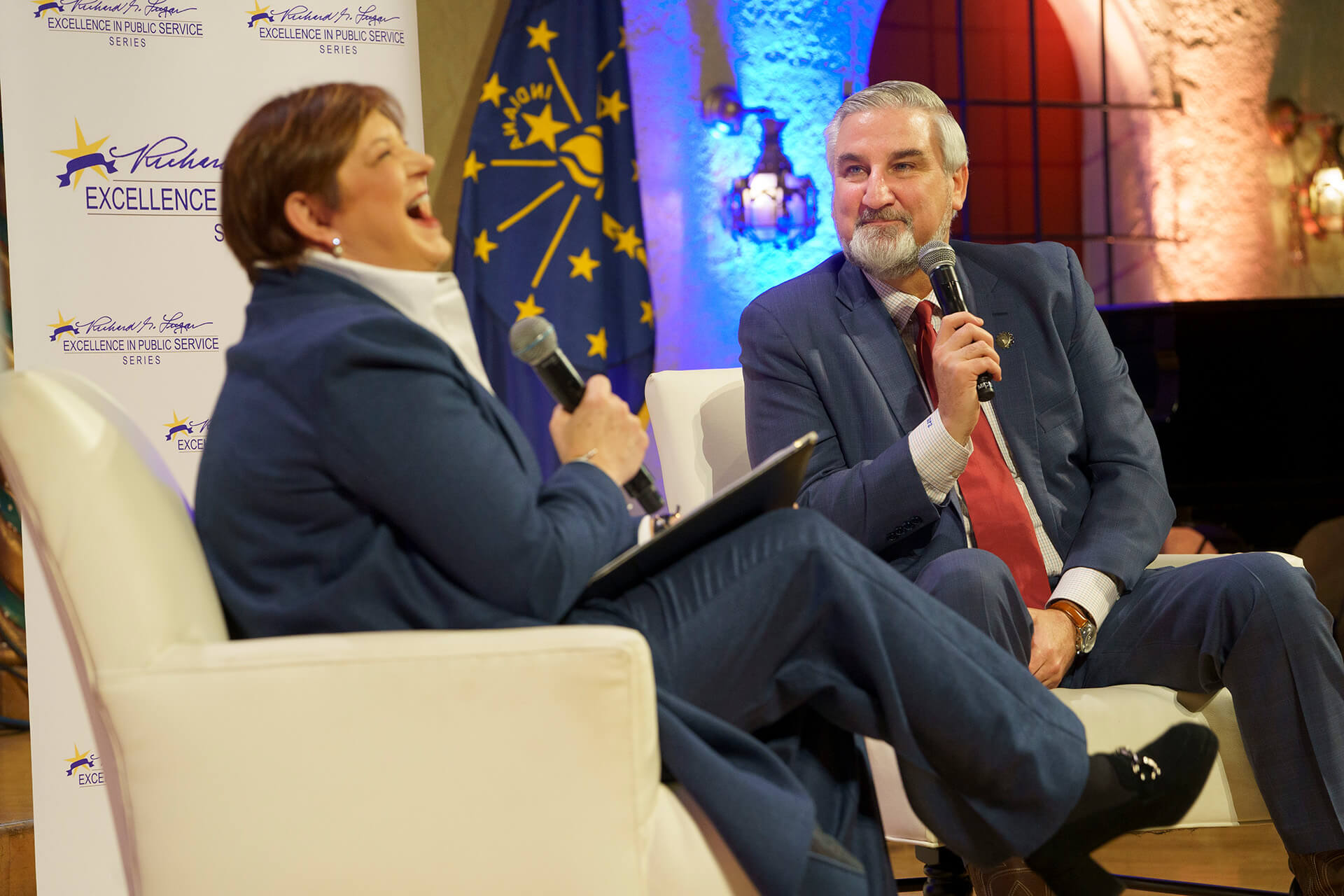 Lugar Series member laughs with a guest speaker on stage