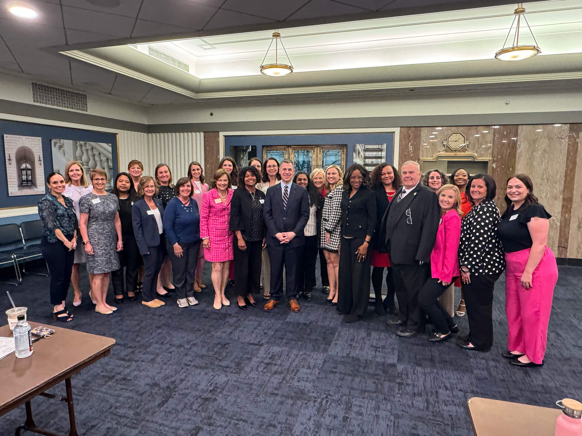 Women of the Lugar Series pose with an event speaker who is wearing a blue suit
