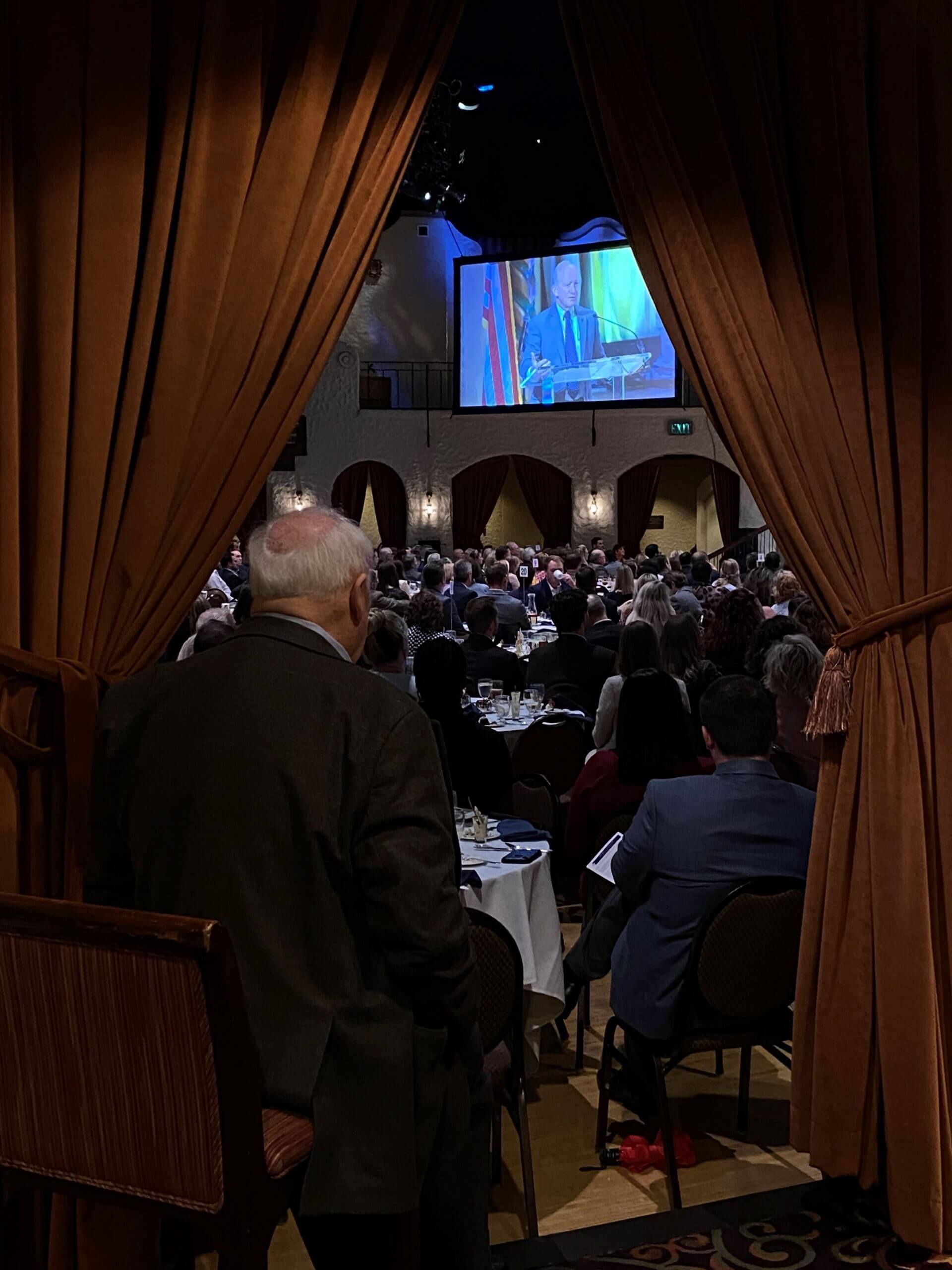 A speaker’s image on a large television at the event